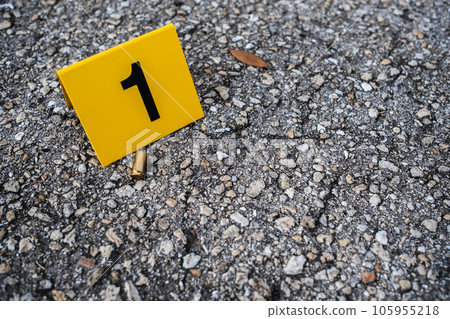 One yellow crime scene evidence marker on the street after a gun shooting brass bullet shell casing 9mm handgun pistol 105955218
