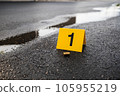One yellow crime scene evidence marker on the street after a gun shooting brass bullet shell casing 9mm handgun pistol 105955219