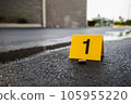 One yellow crime scene evidence marker on the street after a gun shooting brass bullet shell casing 9mm handgun pistol 105955220