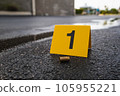 One yellow crime scene evidence marker on the street after a gun shooting brass bullet shell casing 9mm handgun pistol 105955221