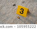 One yellow crime scene evidence marker on the street after a gun shooting brass bullet shell casing 9mm handgun pistol 105955222