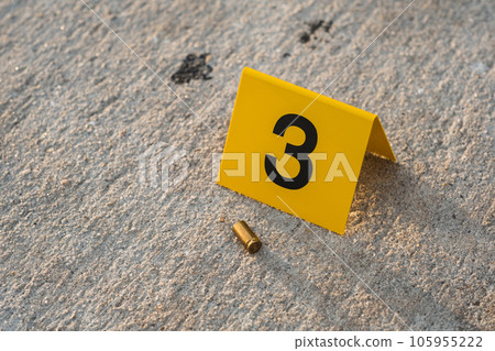 One yellow crime scene evidence marker on the street after a gun shooting brass bullet shell casing 9mm handgun pistol 105955222