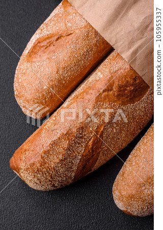 French baguette bread on a dark textured concrete background French baguette bread on a dark textured concrete background 105955337