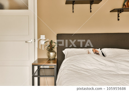 a bedroom with a bed and shelves on the wall next to the bed is an open door that leads to another room 105955686