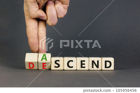 Ascend or descend symbol. Concept words Ascend and Descend on wooden cubes. Beautiful grey table grey background. Businessman hand. Business ascend or descend concept. Copy space. 105956456
