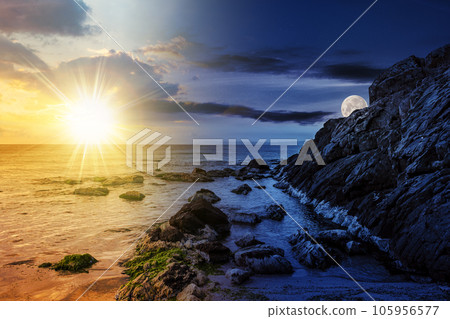 large boulders and seaweed on the rocky coast of the sea with sun and moon at twilight. day and night time change concept. mysterious countryside scenery in morning light large boulders and seaweed on the rocky coast of the sea with sun and moon at twilight. day and night time change concept. mysterious countryside scenery in morning light 105956577