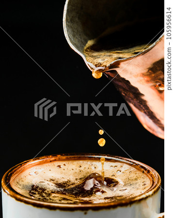 Espresso details. Close-up of pouring coffee into a white cup from a coffee pot, selective focus. The concept of making coffee in a bar, pub or restaurant. Brewing coffee in a cezve. 105956614