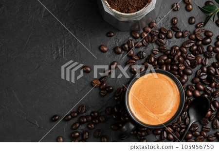 Espresso in a cup on a black table next to a coffee pot. Coffee beans and coffee ingredients on the table. Top view, place for text. Italian style breakfast idea. Espresso in a cup on a black table next to a coffee pot. Coffee beans and coffee ingredients on the table. Top view, place for text. Italian style breakfast idea. 105956750