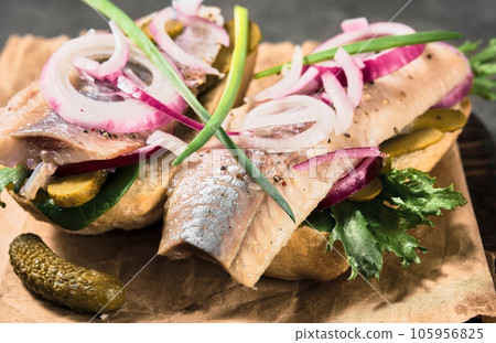 Open sandwich with bread, pickled herring, pickled cucumber and red onion on a paper lining. Danish smorebrod, selective focus and copy space Open sandwich with bread, pickled herring, pickled cucumber and red onion on a paper lining. Danish smorebrod, selective focus and copy space 105956825
