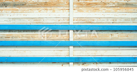 Weathered and sun-bleached wooden boards with remnants of old blue and white paint. Background from old boards with bright patterns. Wall of an old barn in the bright sun Weathered and sun-bleached wooden boards with remnants of old blue and white paint. Background from old boards with bright patterns. Wall of an old barn in the bright sun 105956845