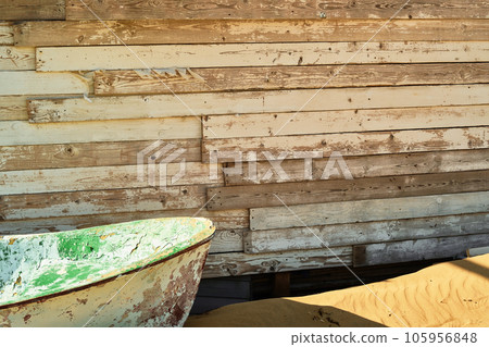 Old boat abandoned on the beach, near a dilapidated wooden shed, close-up, sunlight Old boat abandoned on the beach, near a dilapidated wooden shed, close-up, sunlight 105956848