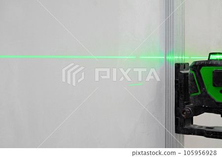 Installation of new tiles on the wall using a laser level. Laser level illuminates the installation site, professional approach 105956928