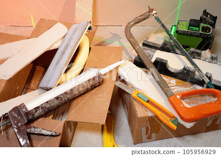 Set of tools for repairing and installing tiles on a cement floor background, flat lay. the concept of repair, construction and repair work - various work tools Set of tools for repairing and installing tiles on a cement floor background, flat lay. the concept of repair, construction and repair work - various work tools 105956929