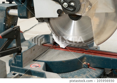 Circular saw with a sharp rotating blade, cuts new baseboard, equipment for renovation and construction. Working circular saw at construction site Circular saw with a sharp rotating blade, cuts new baseboard, equipment for renovation and construction. Working circular saw at construction site 105956930