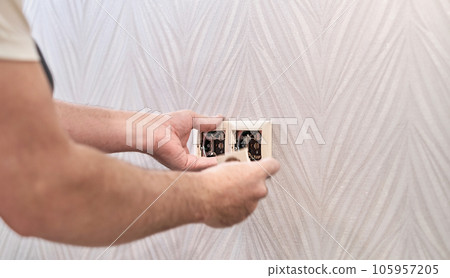 Electrical repair and install socket, outlet plug and switch. An electrician caucasian man install an outlet with pliers during a repair. Hands of the master close-up during work Electrical repair and install socket, outlet plug and switch. An electrician caucasian man install an outlet with pliers during a repair. Hands of the master close-up during work 105957205