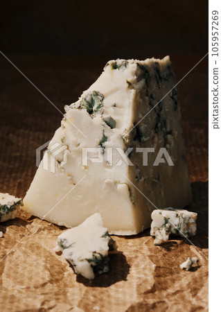 Blue cheese on a paper lining, close-up, selective focus on a piece of cheese 105957269