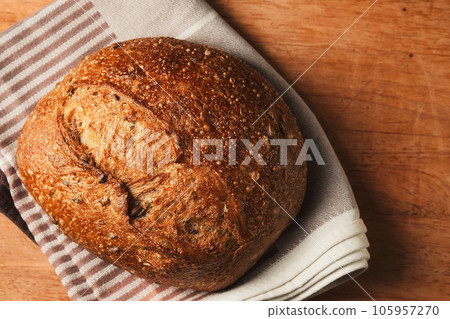 Fresh loaf of bread on a wooden board, loaf of artisan healthy sourdough bread, top view. Fresh loaf of bread on a wooden board, loaf of artisan healthy sourdough bread, top view. 105957270