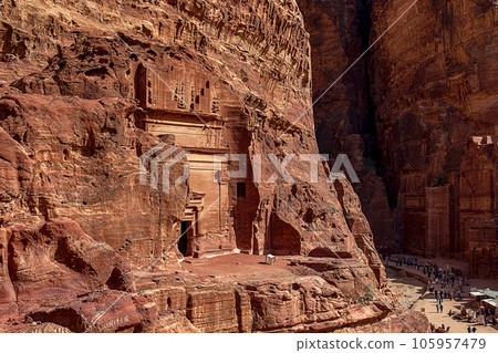 View of the wall with the door, the entrance to the temple, carved into the red sandstone rock in the canyon. Petra, Jordan 105957479