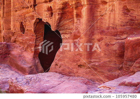 View of the wall with the door, the entrance to the temple, carved into the red sandstone rock in the canyon. Petra, Jordan 105957480