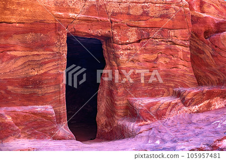 View of the wall with the door, the entrance to the temple, carved into the red sandstone rock in the canyon. Petra, Jordan 105957481