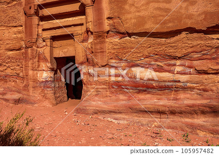 View of the wall with the door, the entrance to the temple, carved into the red sandstone rock in the canyon. Petra, Jordan 105957482