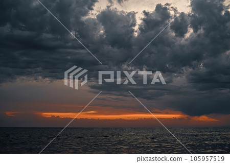 Beautiful sunset over the sea with gray dramatic clouds and orange sunset streak, dramatic sky Selective focus on the clouds 105957519