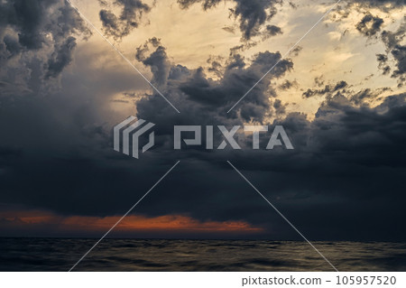 Beautiful sunset cloudy pre-stormy sky and dark sea water, evening seascape. Horizontal color photograph. Selective focus on the clouds 105957520