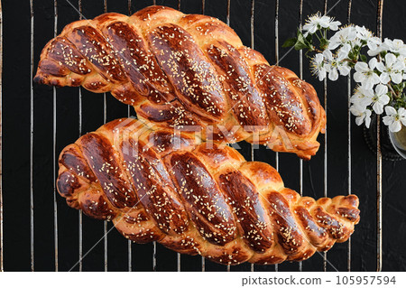 Homemade jewish challah bread, top view. From above, overhead. Sweet holiday bread sprinkled with sesame seeds cools down after baking, flat lay Homemade jewish challah bread, top view. From above, overhead. Sweet holiday bread sprinkled with sesame seeds cools down after baking, flat lay 105957594