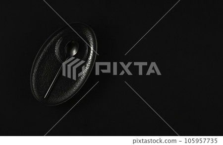 Coffee black saucer with a dessert spoon on a black table, top view with copy space. Minimalist breakfast idea in black. 105957735