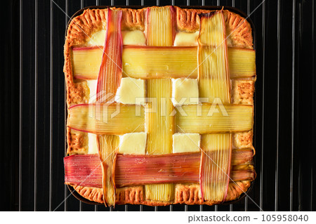 Beautiful delicious rhubarb tart, freshly baked homemade traditional tart pan, top view, flat lay with colorful checkered rhubarb stalks. Spring and summer sweet and sour cake Beautiful delicious rhubarb tart, freshly baked homemade traditional tart pan, top view, flat lay with colorful checkered rhubarb stalks. Spring and summer sweet and sour cake 105958040