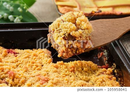 Traditional English crumbly rhubarb pie with baked filling or delicious rhubarb pie. Close-up, soft selective focus on a slice of pie on a shoulder blade Traditional English crumbly rhubarb pie with baked filling or delicious rhubarb pie. Close-up, soft selective focus on a slice of pie on a shoulder blade 105958041