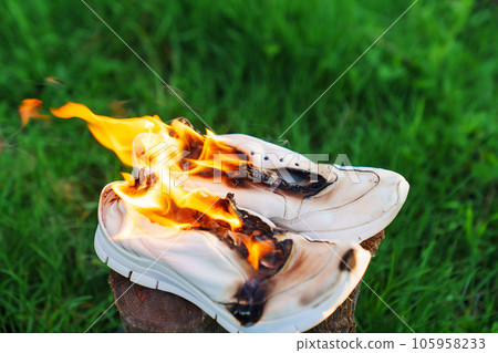 Burning leather sports shoes. Sneakers or gym shoes on fire stand on the Stump. 105958233