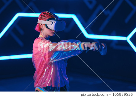 Young female gamer in pink is playing virtual reality games. VR headset and controllers. 105959536
