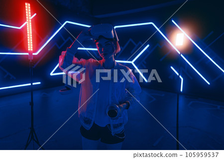Young female gamer in pink is playing virtual reality games. VR headset and controllers. 105959537