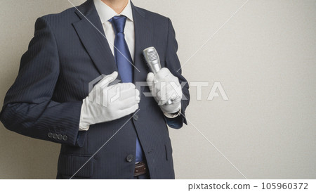 A man wearing a suit holding a microphone with white gloves 105960372