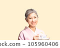 A middle-aged woman with gray hair wearing a kimono and drinking tea 105960406