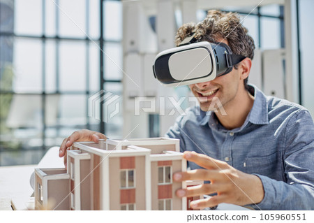 man sits in the office of a realtor and looks at the layout of the apartment in virtual reality glasses. man sits in the office of a realtor and looks at the layout of the apartment in virtual reality glasses. 105960551