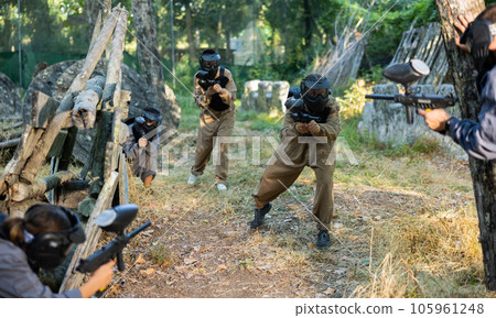 Group of friends paintball players of opposite teams in shootout in forest 105961248
