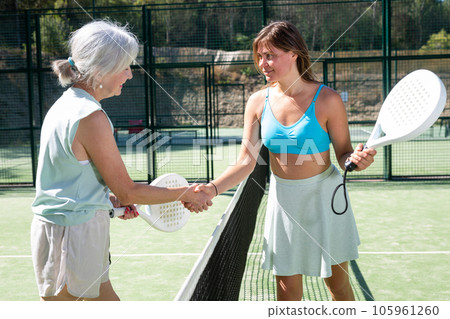 Senior and young women handshaking after padel tennis match 105961260