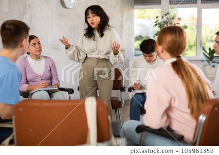 Young Chinese girl student discussing learning assignment with coursemates 105961352