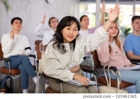 Group of high school students raising hands in auditorium 105961365