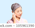 A middle-aged woman with gray hair wearing a kimono and touching her hair 105961390
