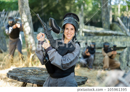 Portrait of smiling woman in uniform with paintball gun 105961395
