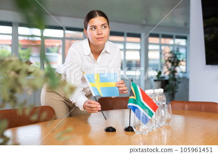 Positive young woman putting little flag of Sweden on table next to the flag of South Africa 105961451