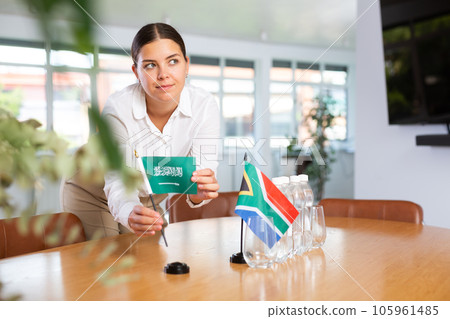 Businesswoman arranging the flags of Saudi Arabia and South Africa for presentation and negotiations Businesswoman arranging the flags of Saudi Arabia and South Africa for presentation and negotiations 105961485
