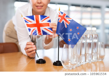 Preparing for business presentation - secretary places flags of Great Britain and Australia on negotiating table 105961534