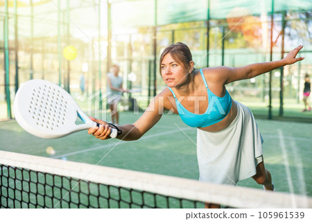 Woman playing padel tennis match during training on court Woman playing padel tennis match during training on court 105961539