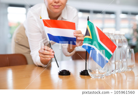 Businesswoman arranging the flags of South Africa and Netherlands for presentation and negotiations Businesswoman arranging the flags of South Africa and Netherlands for presentation and negotiations 105961560