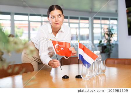 Young woman puts flags of Turkey and Netherlands on table in office Young woman puts flags of Turkey and Netherlands on table in office 105961599