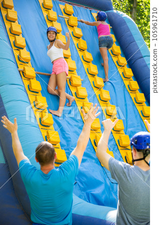 Women using sticks to reach top of slide in adventure park 105961710